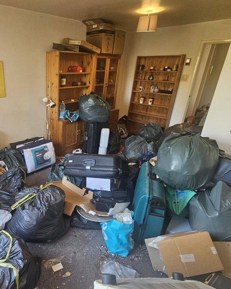 A room being cleared, with display shelves and household belongings bagged up in front of them